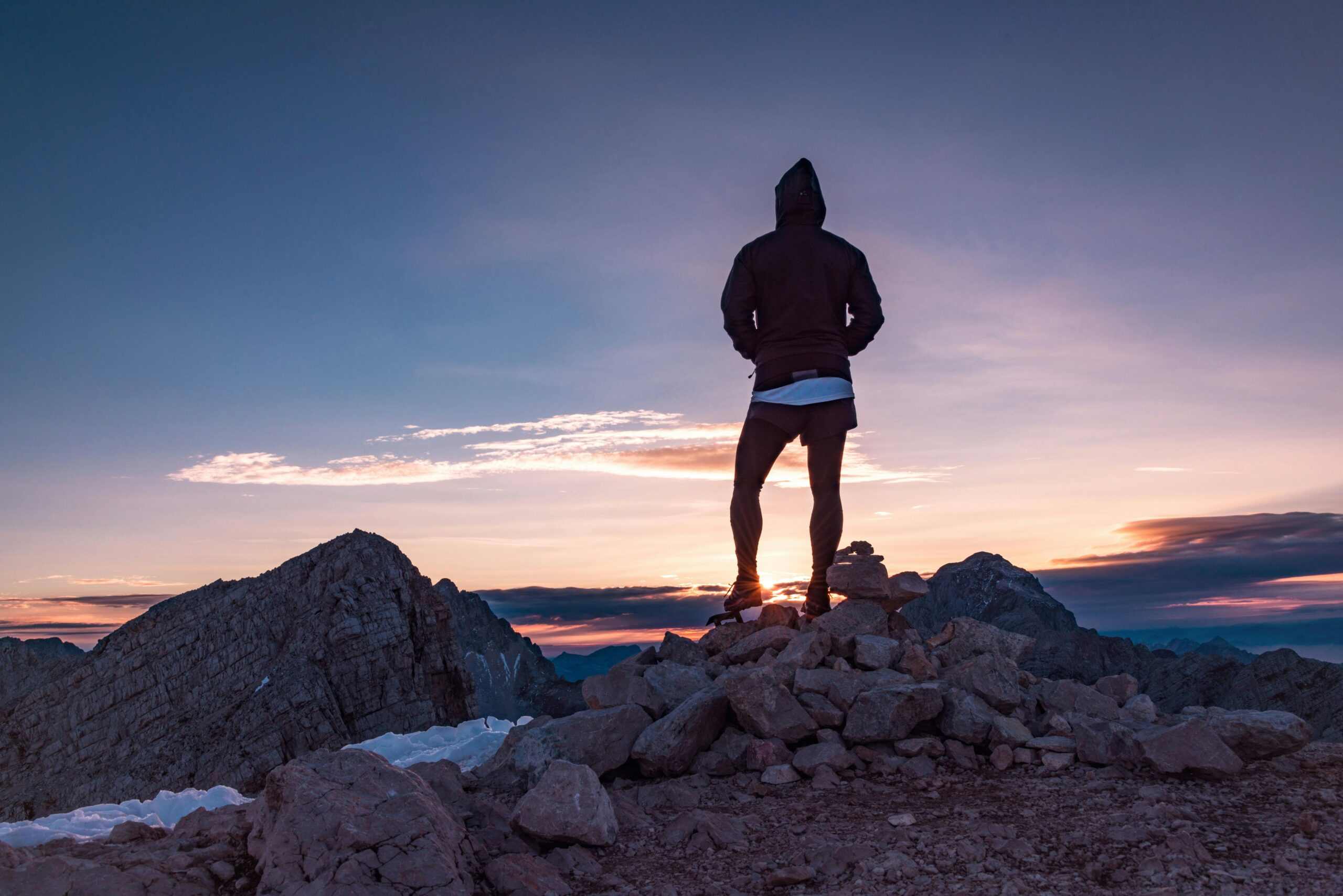 Person standing on a mountain summit at sunrise symbolizing hope, progress, and the positive direction people experience in sobriety.